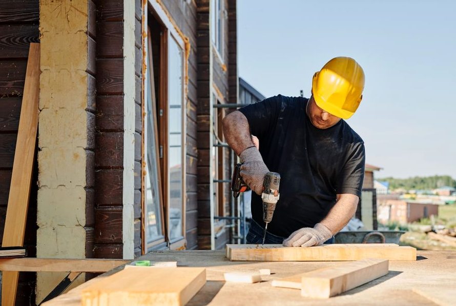 A construction worker using a power drill on a building site, outdoors during the day