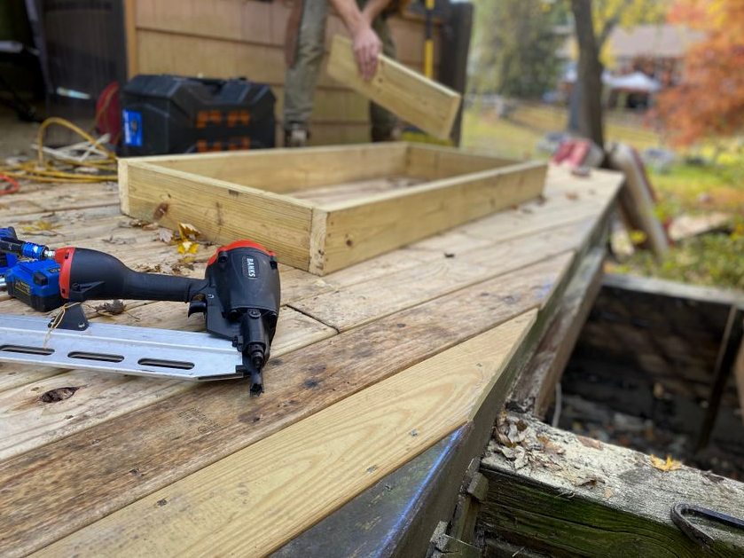 Close-up of carpentry work on a deck with a nail gun and wooden frame under construction